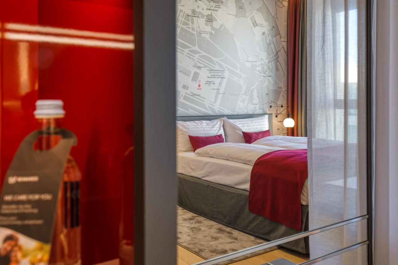 Intercityhotel Berlin Airport Ber Terminal 1 & 2 Schönefeld Exterior foto The photo shows a modern hotel room that features a comfortable bed with white linens and a red accent blanket. Behind the bed is a stylish wall displaying a map design. The room has large windows dressed with light-colored curtains, allowing natural